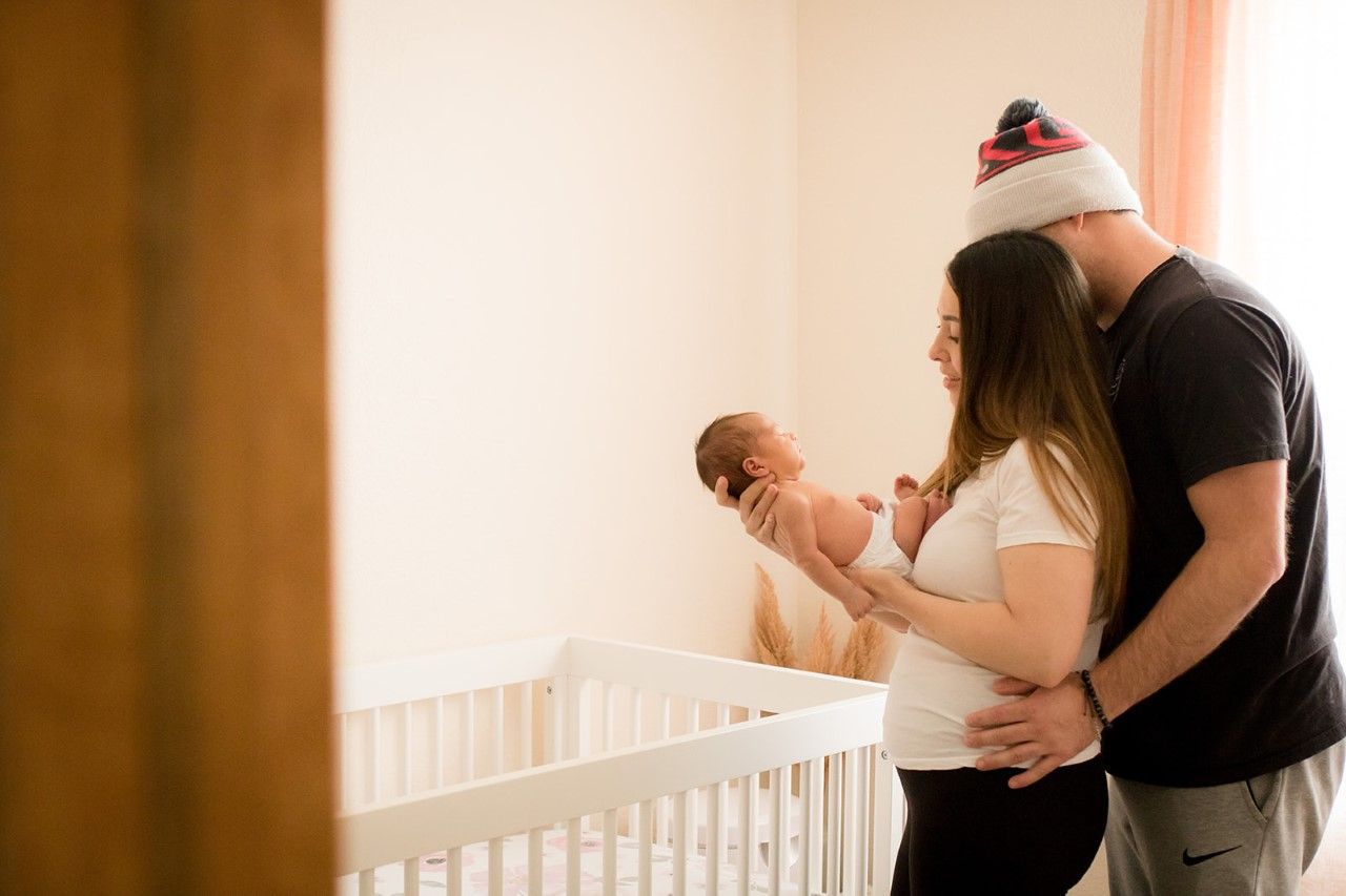 Parents holding their newborn daughter in her nursery during their Colorado newborn photography session