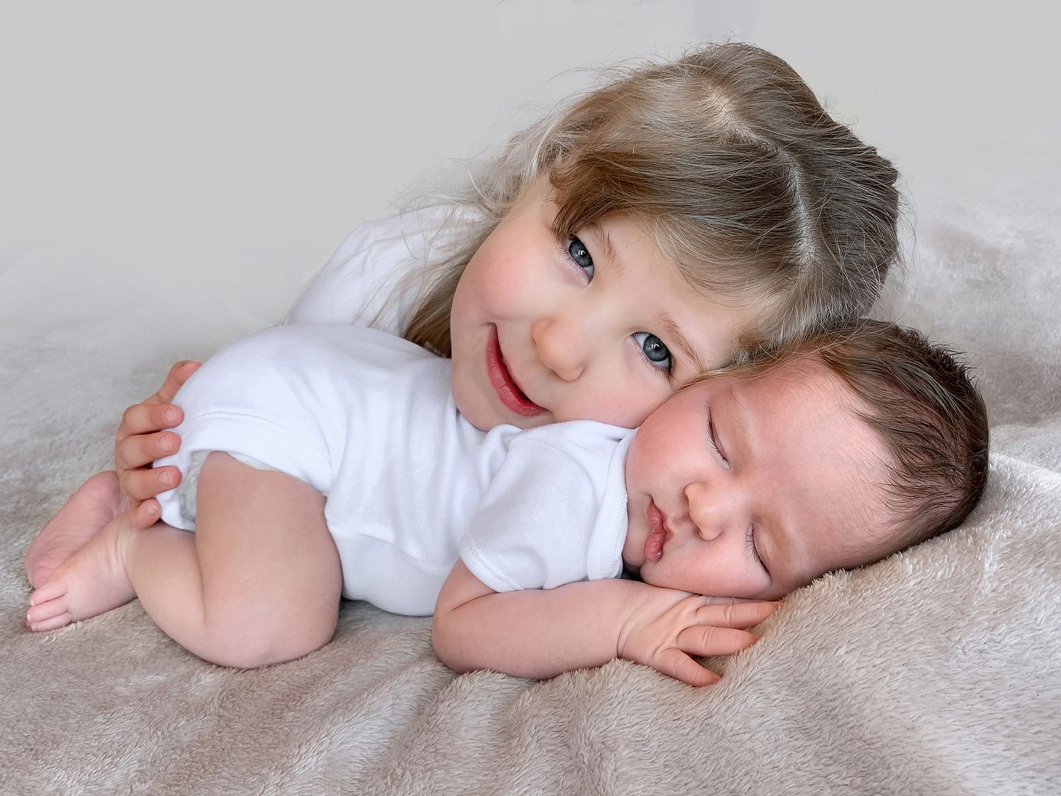 a photo of a toddler girl with her newborn baby sister from a photoshoot in didcot