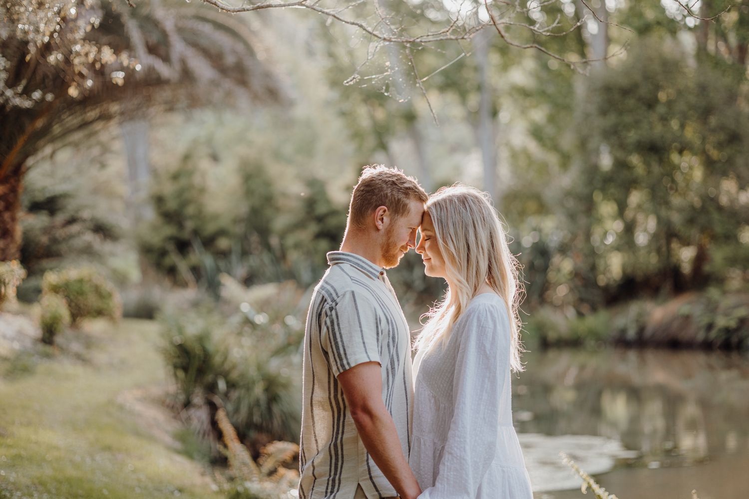 A romantic scene by a garden pond with sunlight filtering through trees.