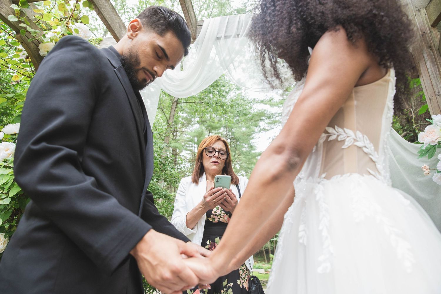 An intimate wedding ceremony moment captured from a unique low angle under a garden pergola.
