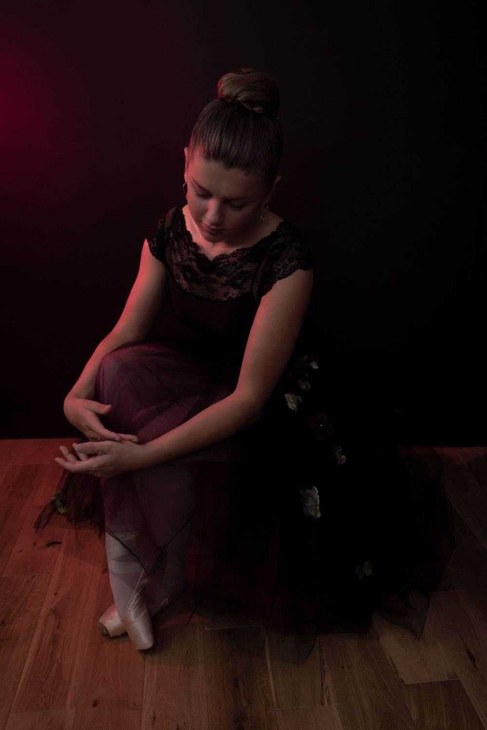 A ballerina sits on the floor wearing pointe shoes and a romantic tutu.