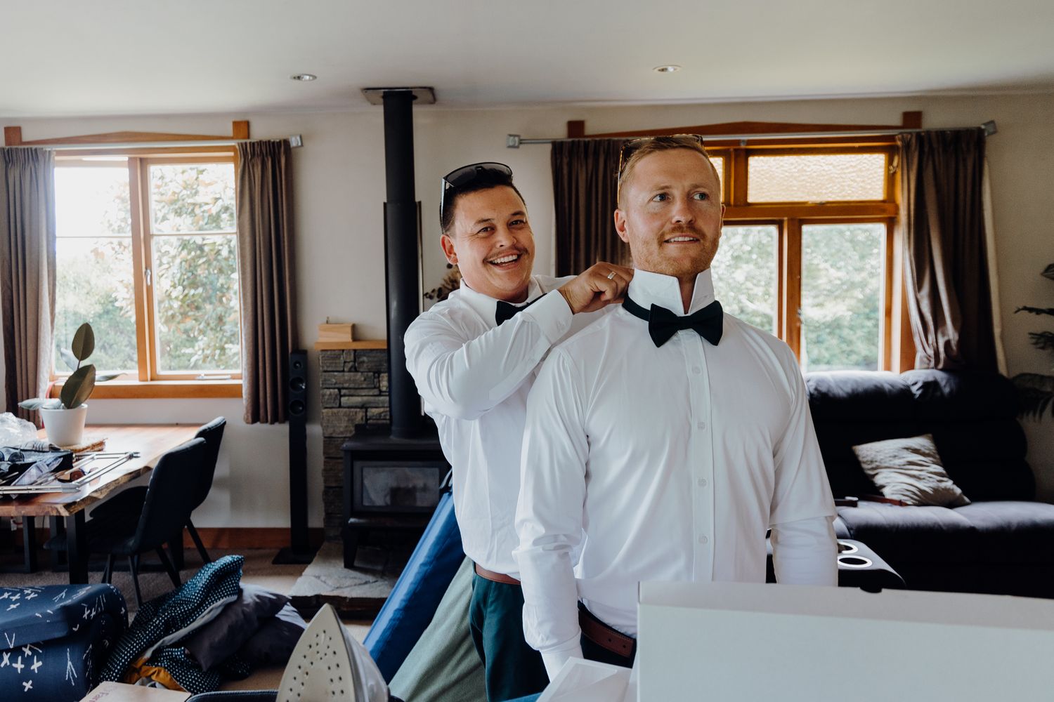 A bow tie being adjusted on someone wearing formal white attire.
