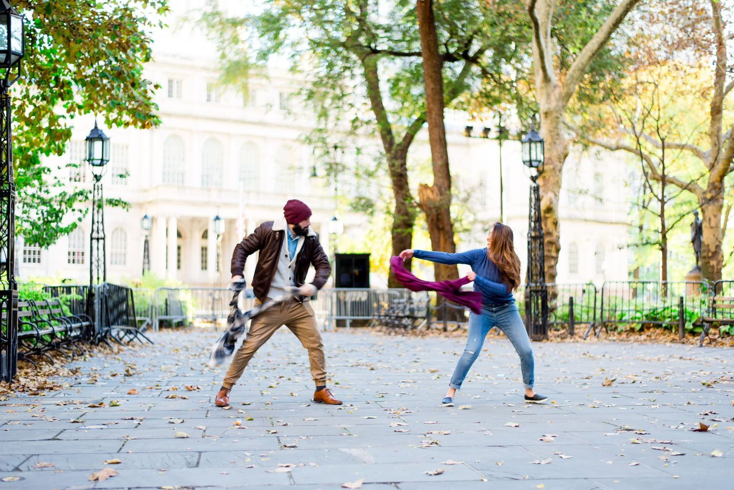 young engaged couple fights with scarves for fun engagement pictures in New York City city Hall