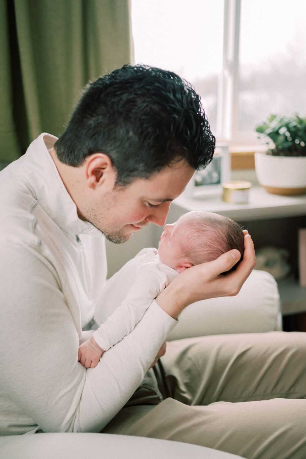 Intimate portrait of parent holding sleeping newborn in white.