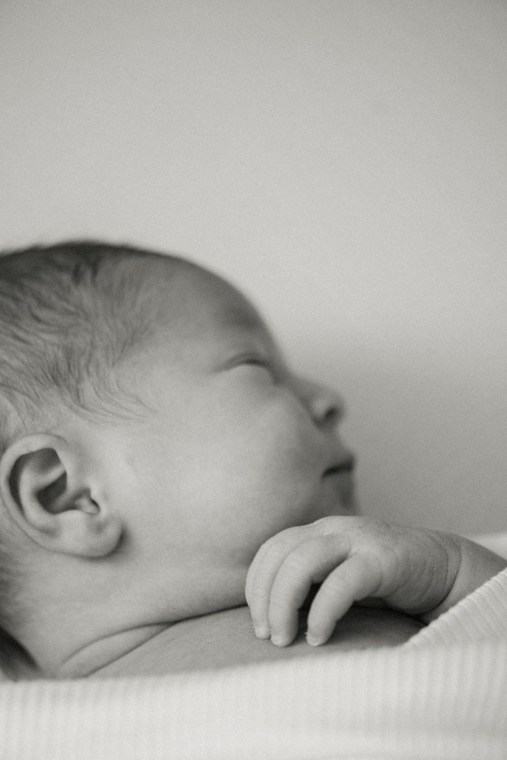 Close-up black and white profile of sleeping newborn showing delicate features.