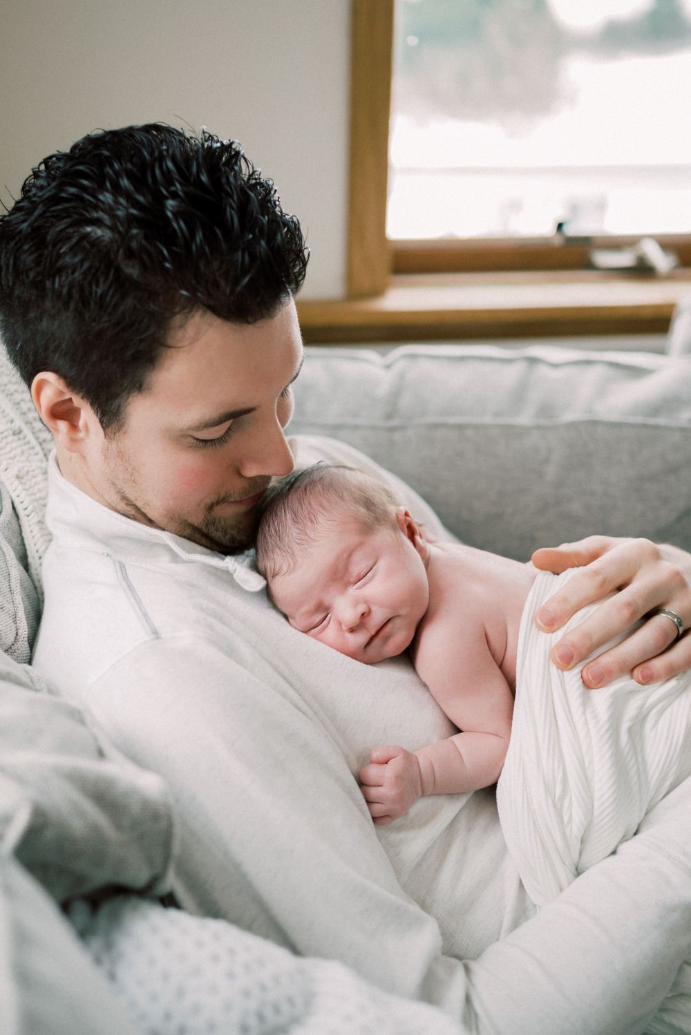 Tender moment of father holding sleeping newborn on his chest.
