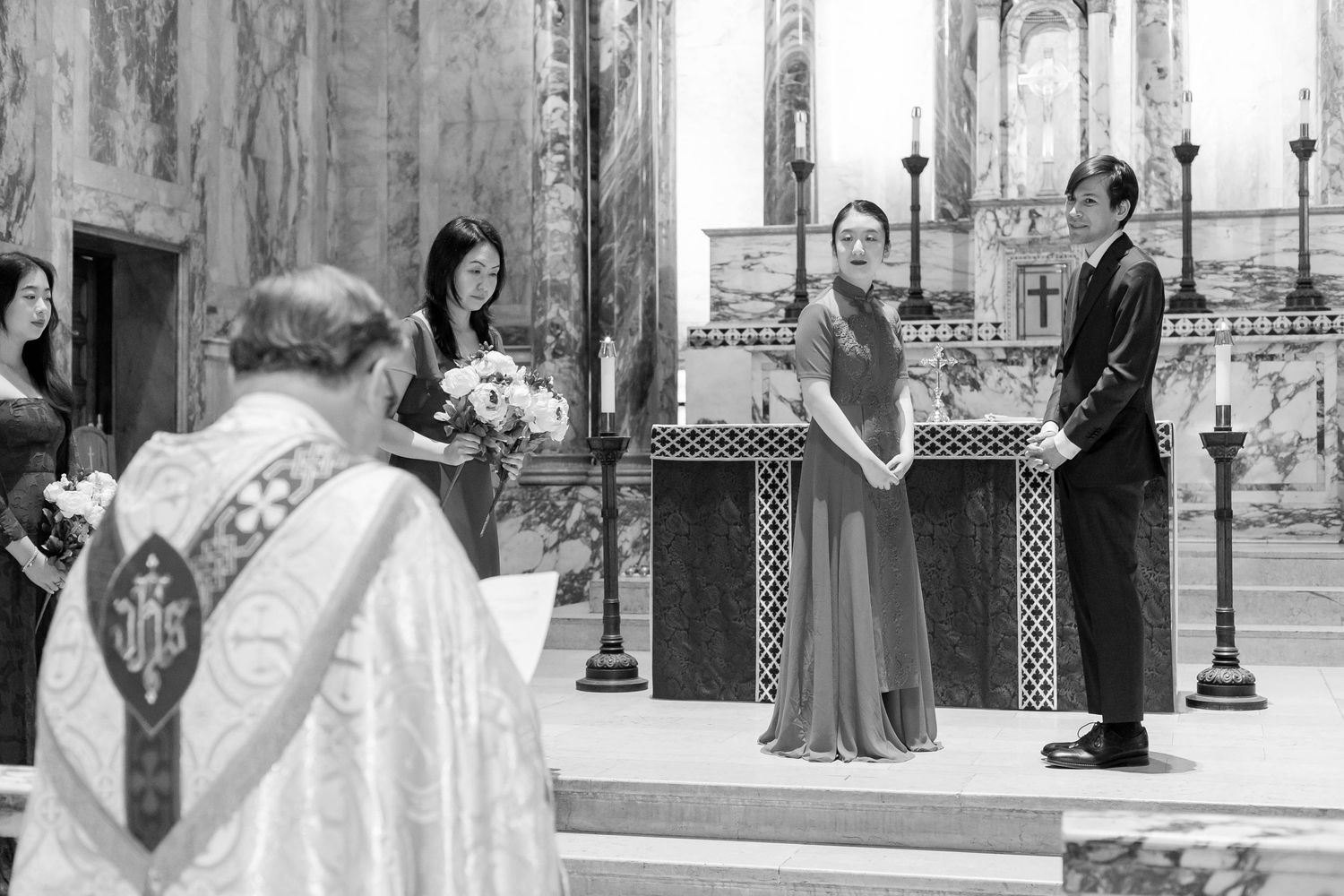 Black and white photo of church ceremony with priest and attendees at ornate altar.
