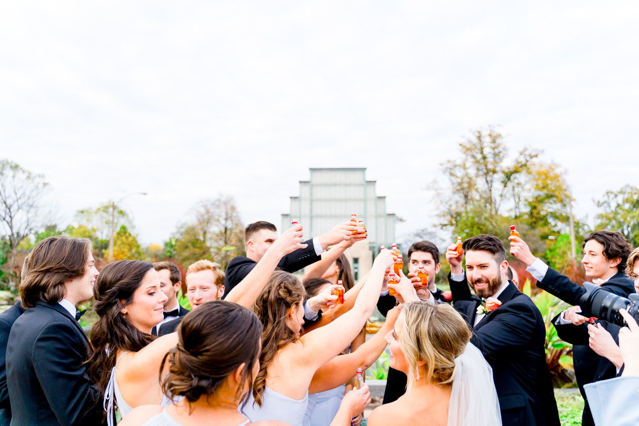 large wedding party clinking together shot bottles of Fireball for fall wedding in STL
