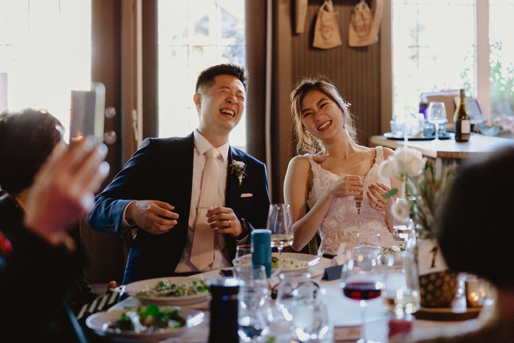 Bride and groom sharing a joyful moment during wedding reception dinner | Calgary wedding photographers..