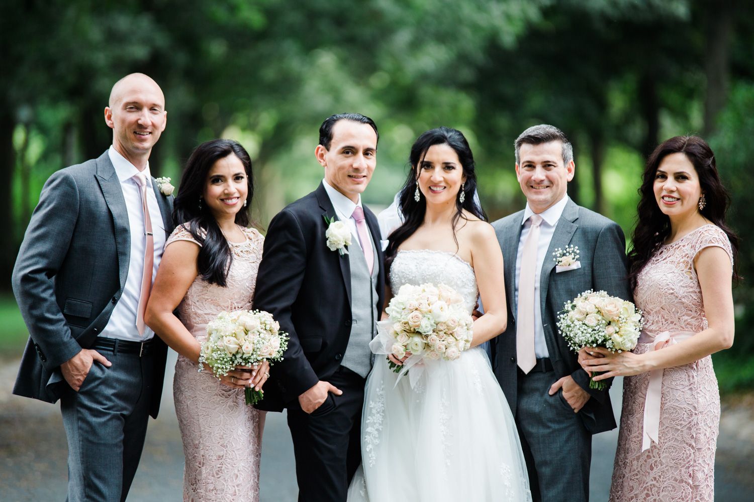 Wedding party with bridesmaids in blush lace and groomsmen in grey suits