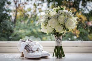Bridal wedding shoes on a windowsill with a bouquet of flowers.