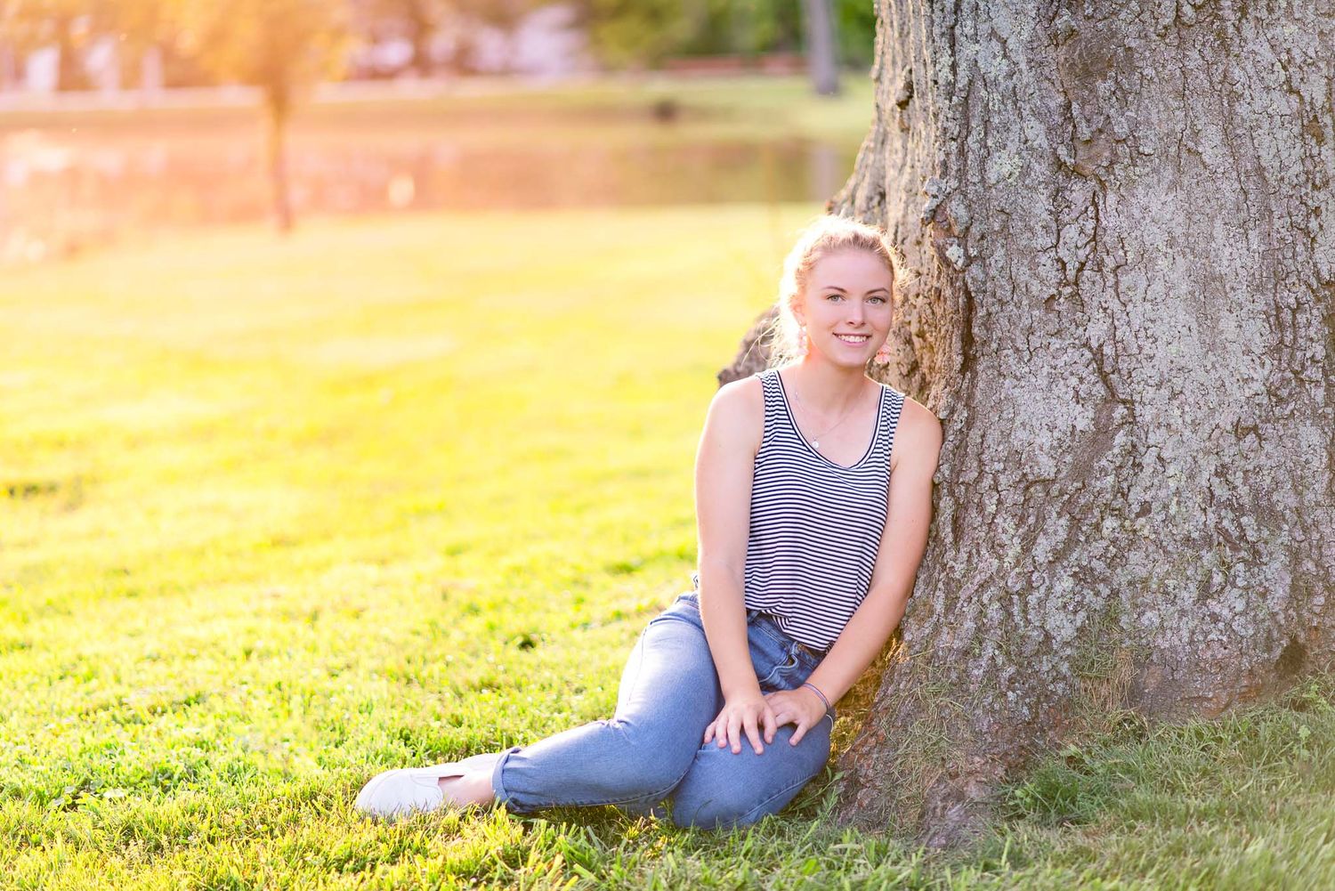 blonde young woman leaning against big tree trunk at sunset in Cincinnati Ohio