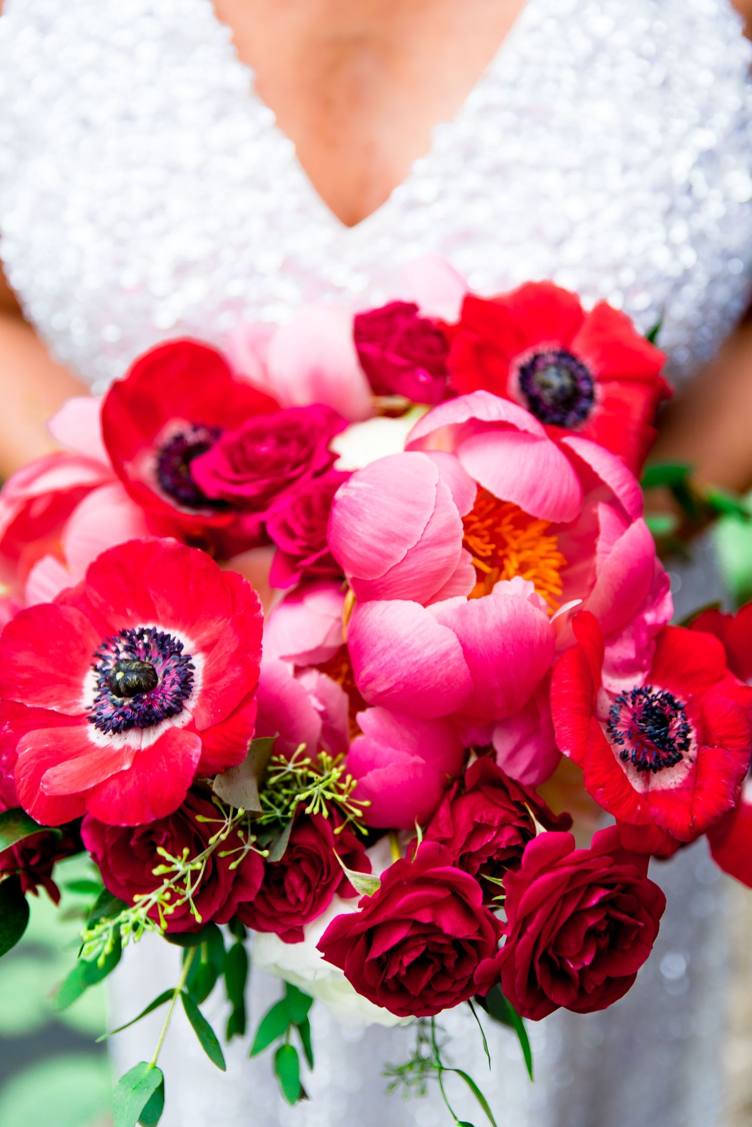woman holding red and pink rose and peony and anemone bouquet