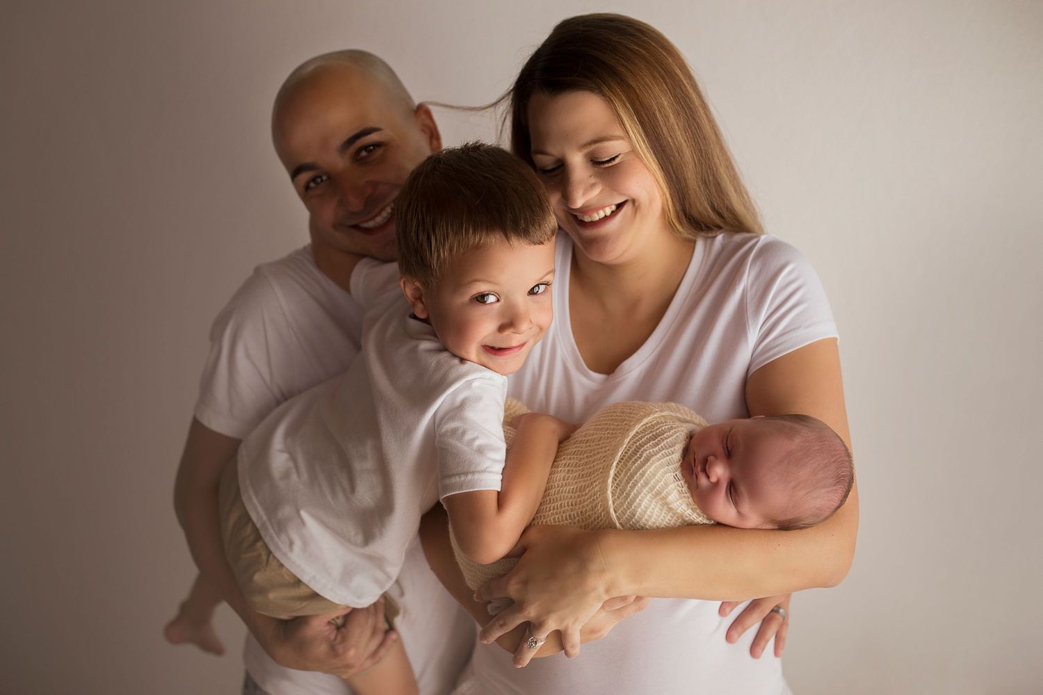 cheeky big brother with laughing parents with new baby brother