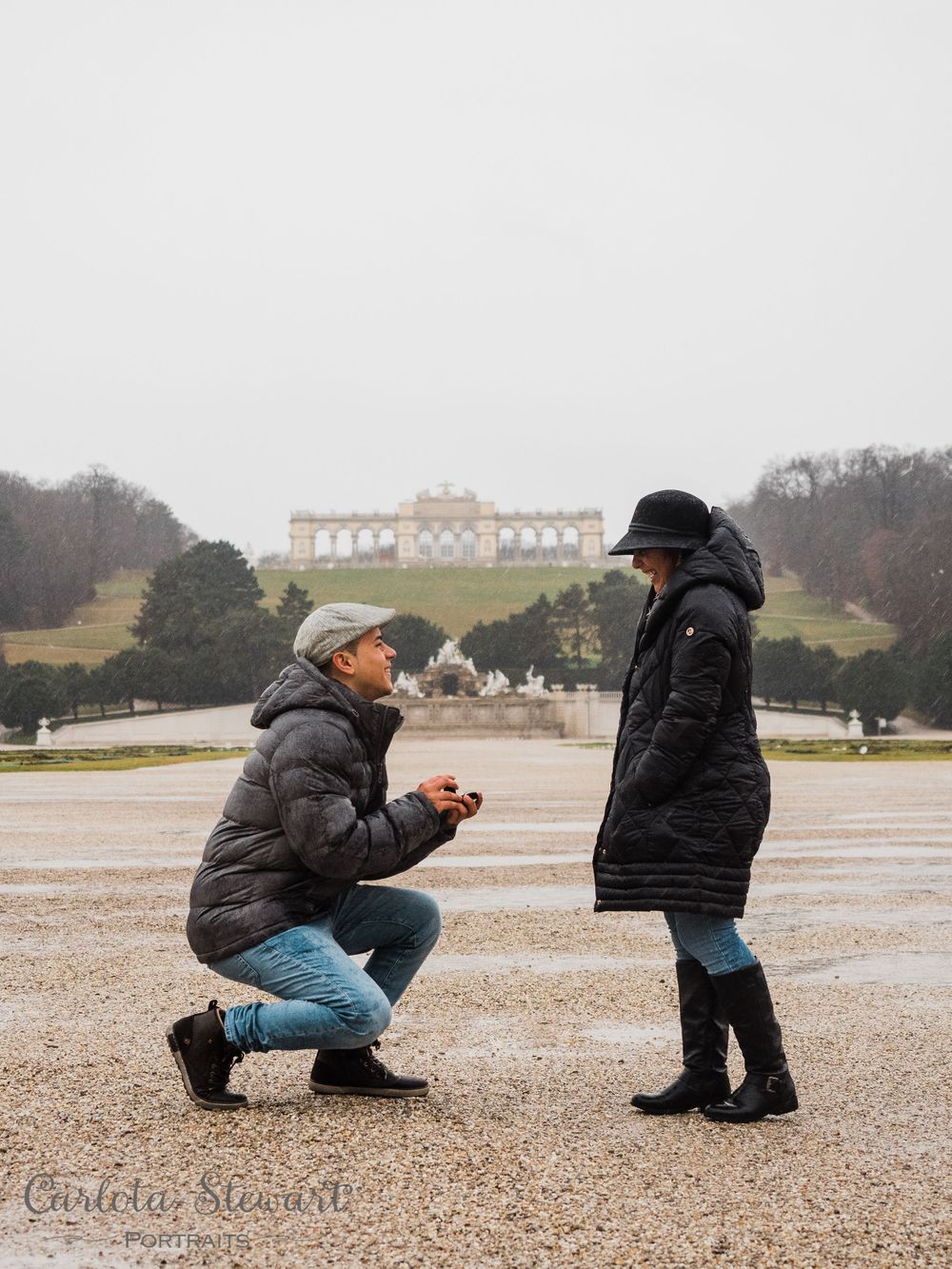 Surprise engagement photograpy of a man offering a ring to girlfriend in Schönbrunn palace gardens, Vienna, Austria