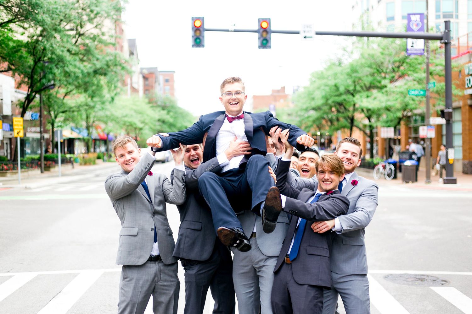 groomsmen in gray suits lift up groom in the streets of Chicago