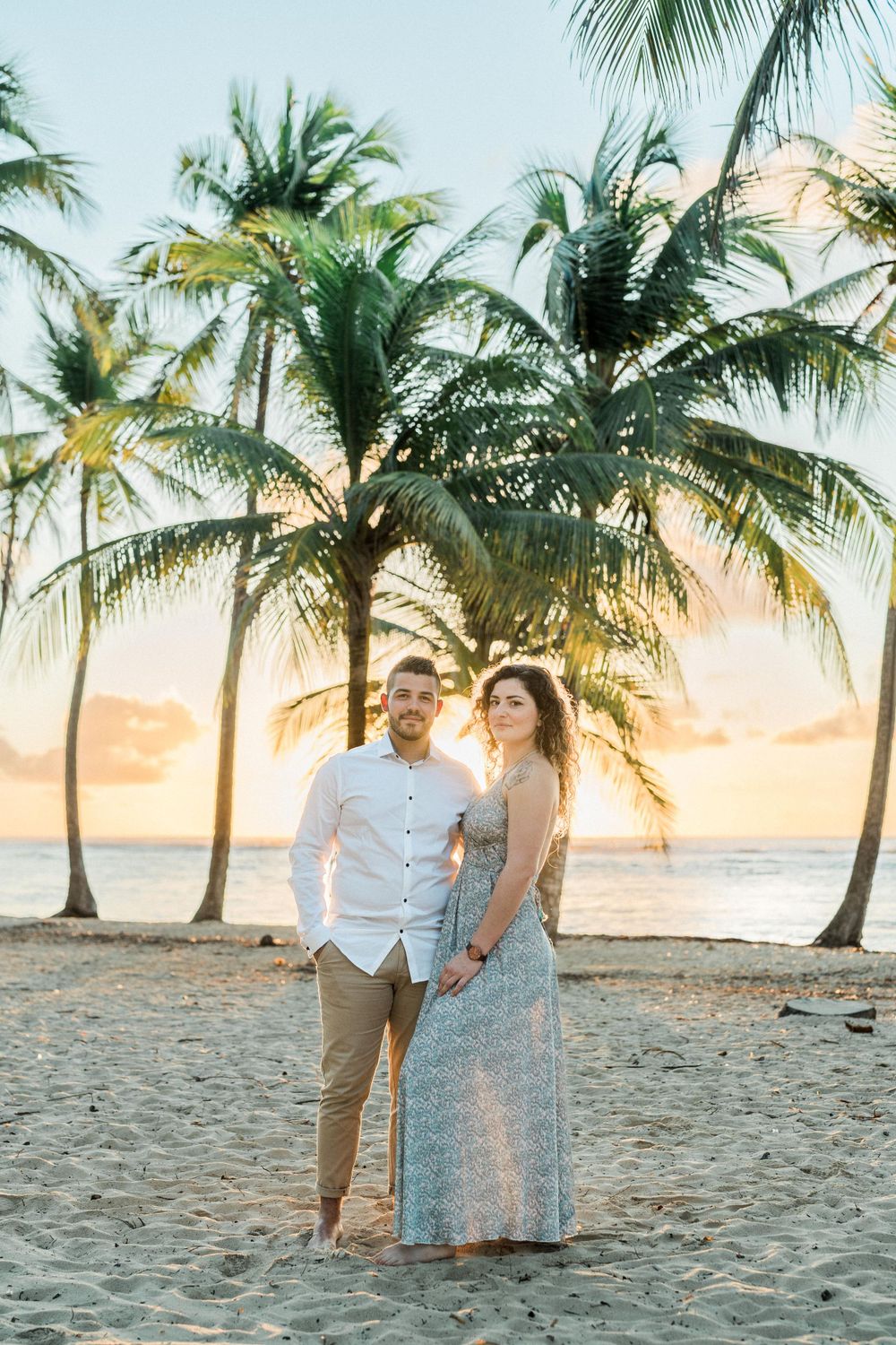 Amoureux qui pose face caméra sur une plage au lever du soleil