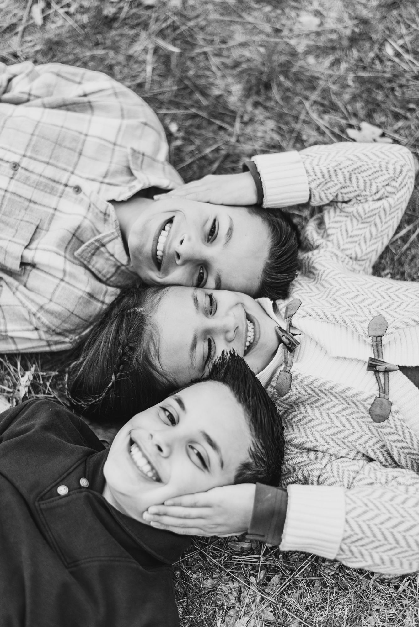 Family session with siblings in black and white lying on ground at North Park, Pittsburgh, Pennsylvania