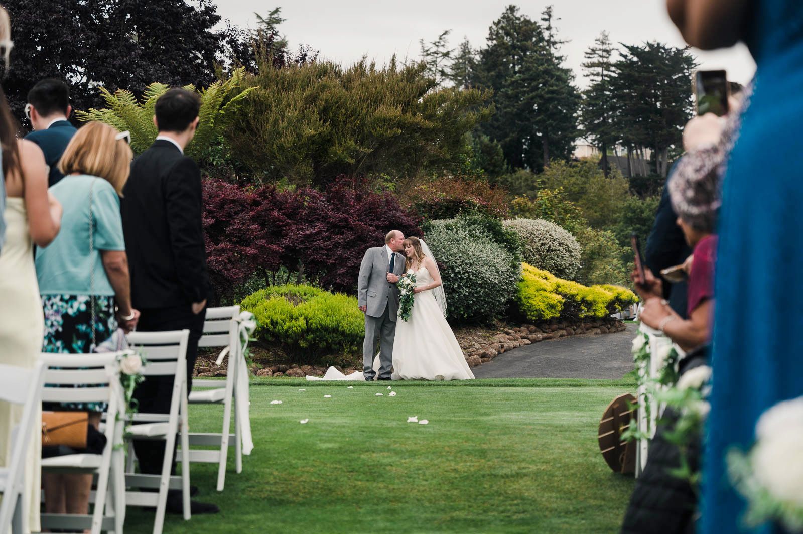 father of the bride giving his daughter a kiss on the forehead before walking her down the aisle to get married