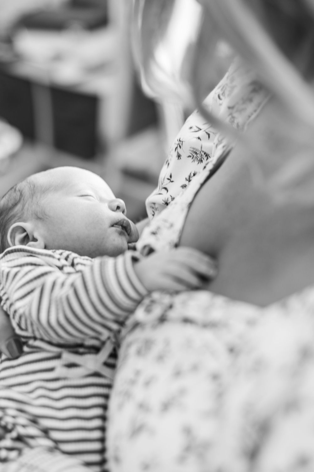 Black and white photo of a newborn in striped clothing being cradled.