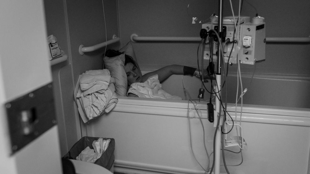 Mother laboring in the tub during her hospital birth. Birth photography by Catherine Rose Photography