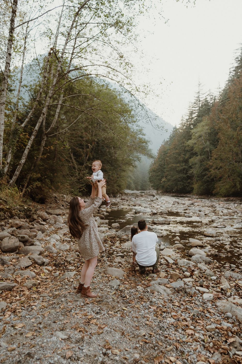 Mother holding up baby boy in air with mountain backdrop