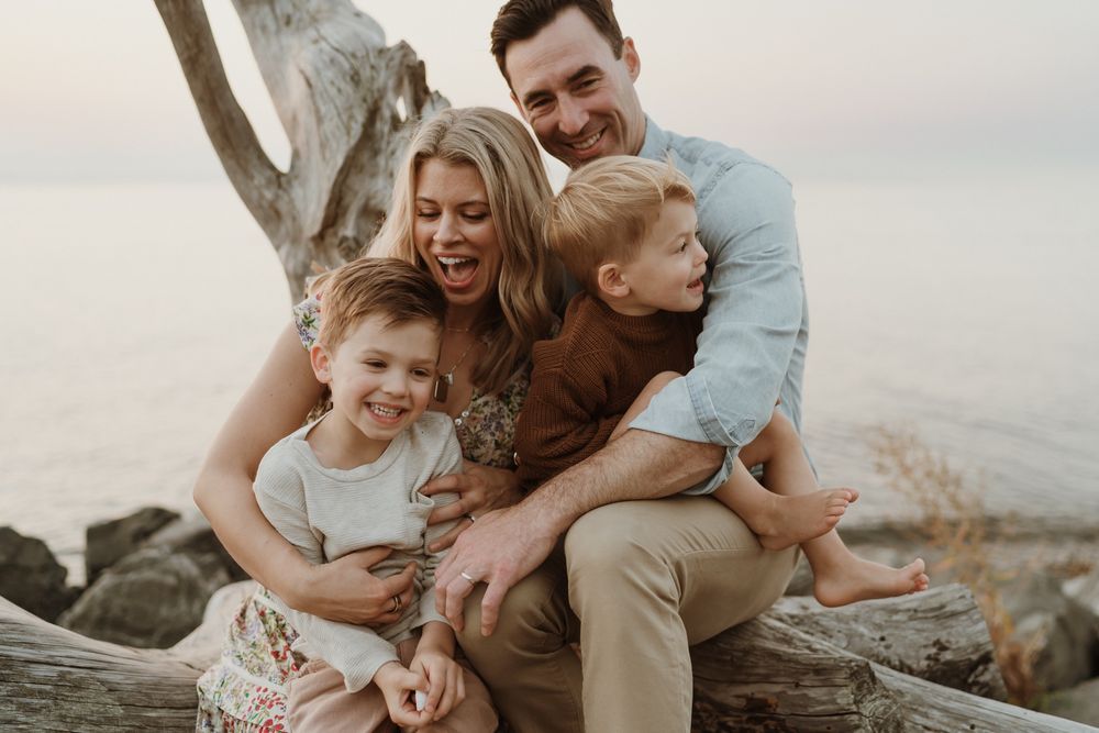 Family of four sitting on driftwood with little boys at Lincoln Park