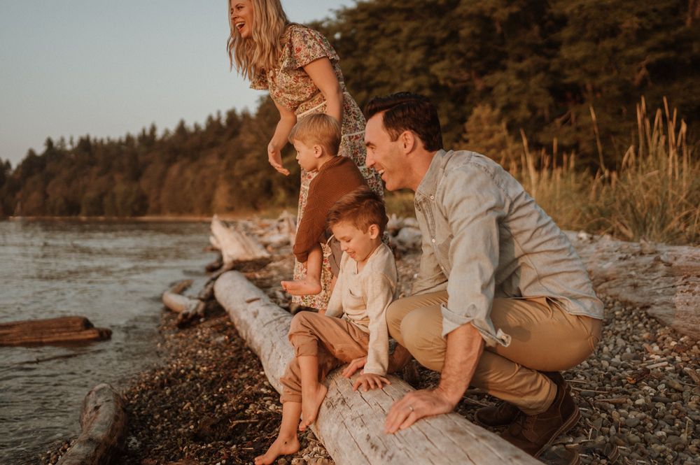 Family of four leaning and standing on driftwood log at sunset at Lincoln Park