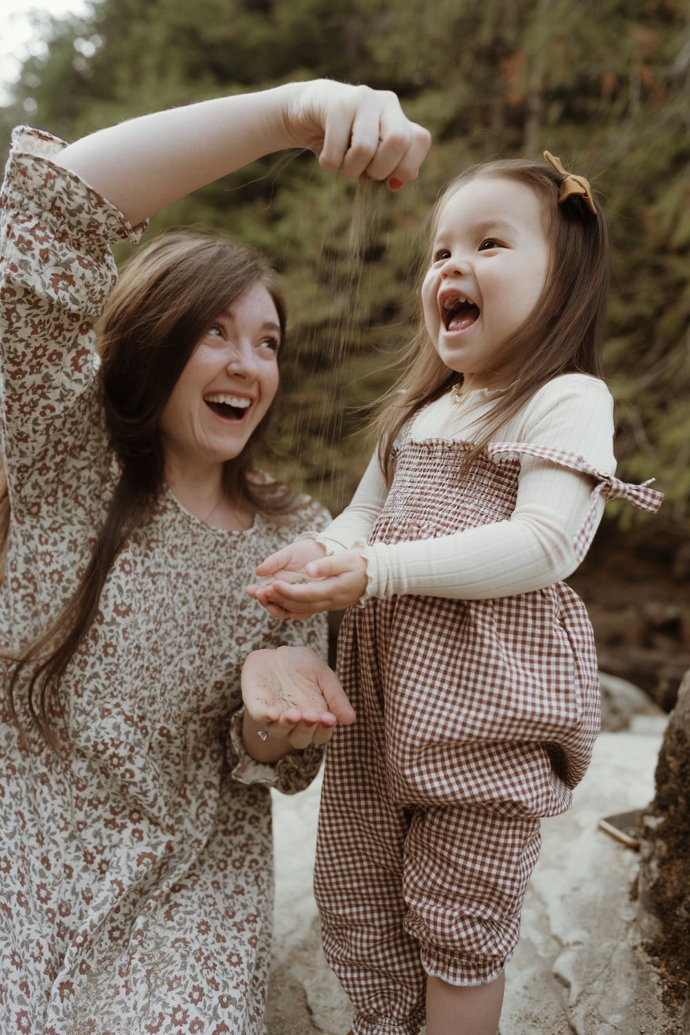 Mother pouring sand up high into little girls hand