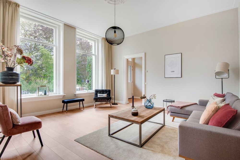 Lichte, smaakvol gedecoreerde woonkamer met doorkijk naar de hal.