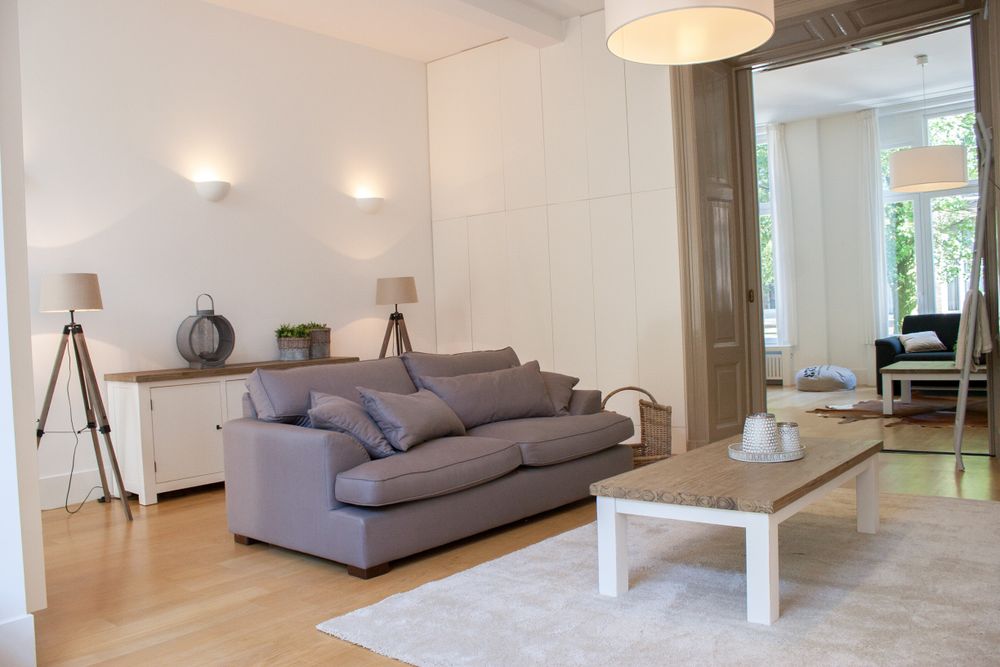 Huiskamer in landelijke stijl: grijze bank met kussens, en matchende dressoir en salontafel in wit/houtkleur