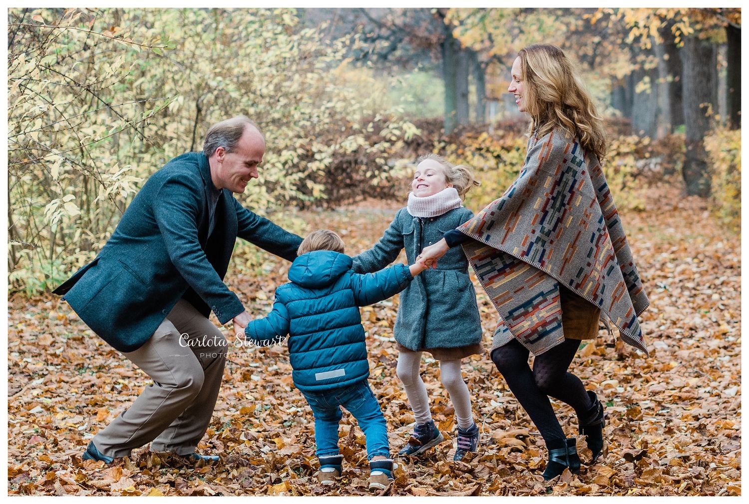 Family of 4 dancing in a park in Autumn with yellow scenery in Vienna Austria