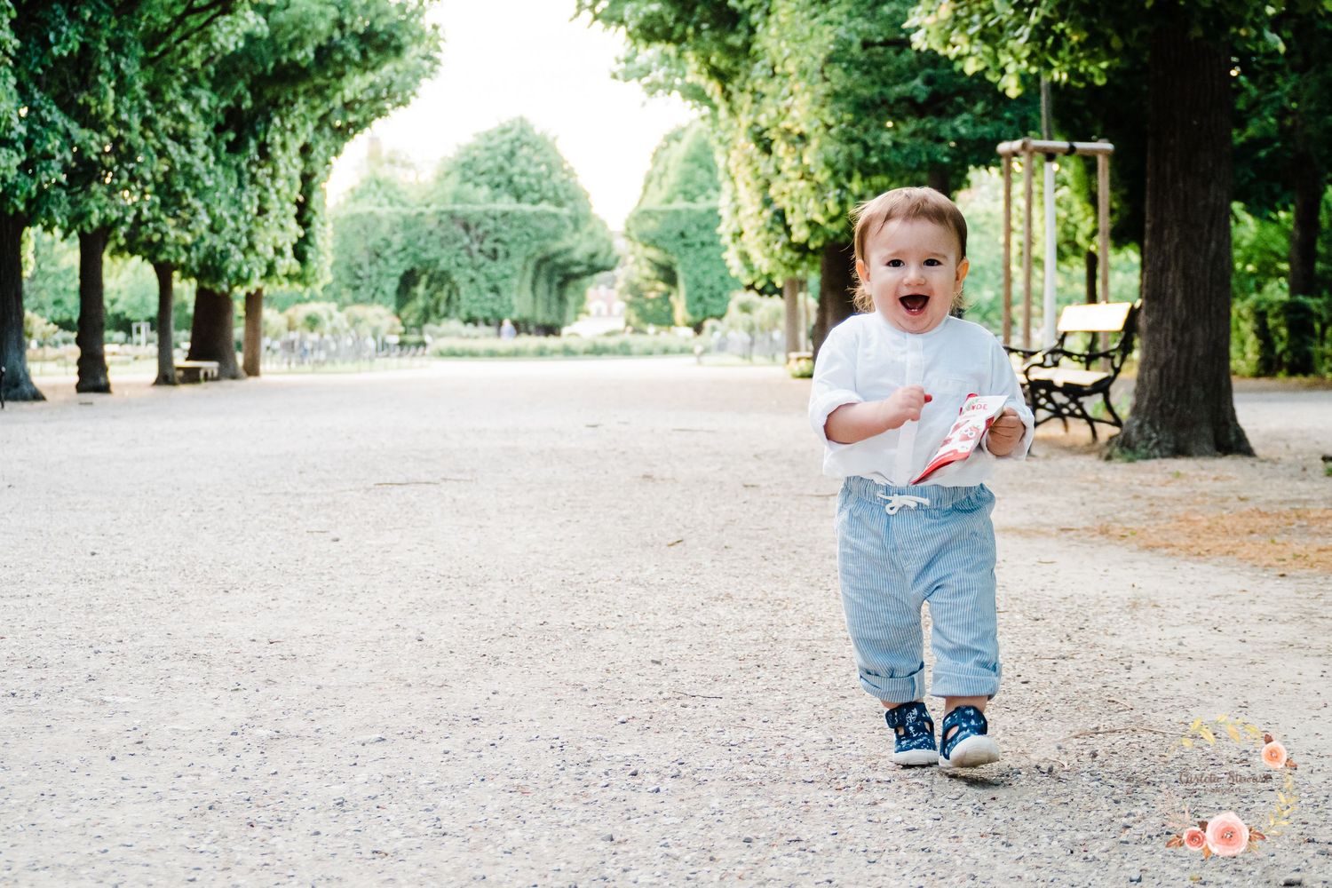 1 year old toddler running thru the Schönbrunn gardens in Vienna wearing a white top and blue trousers.