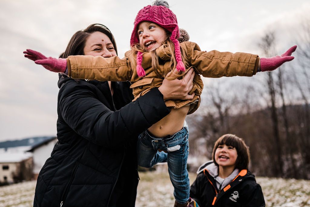 mum playing with her daugher like an aeroplane in mountains in austria