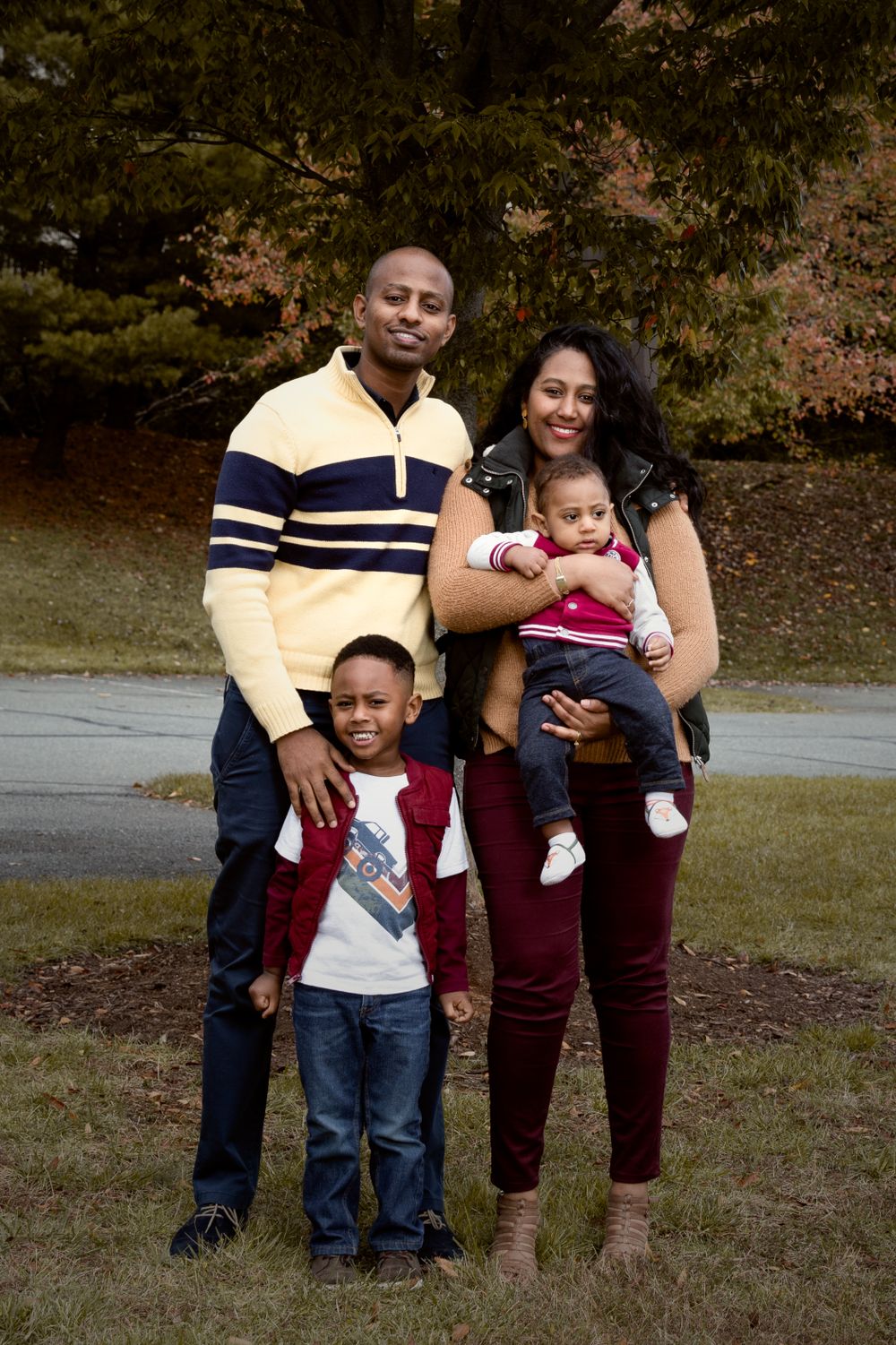 A family portrait outdoors with everyone wearing casual fall attire.
