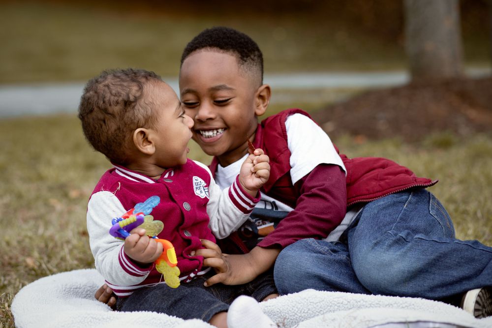 Two children share a playful moment while sitting together outdoors.