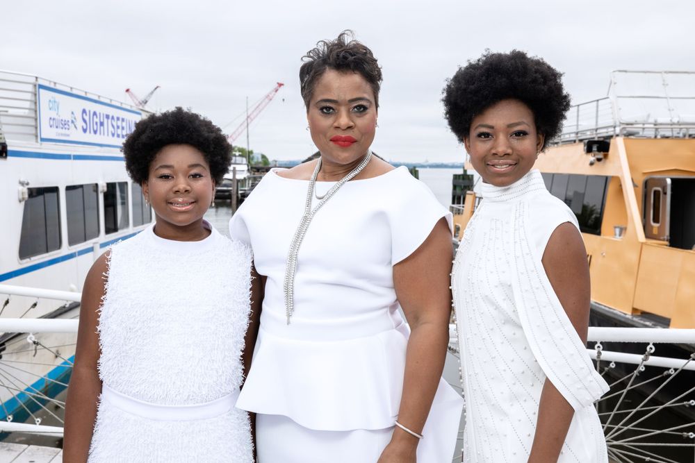 Family in coordinated white outfits pose together at a marina.