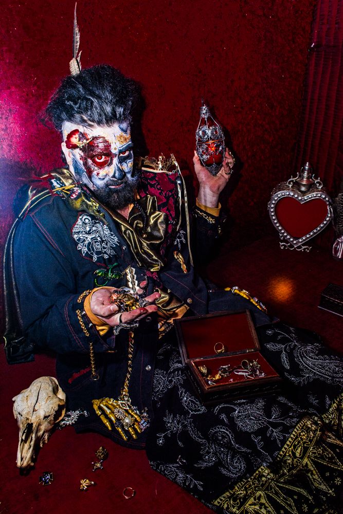 Gothic styled scene with jewelry box, animal skull and heart decoration against red backdrop.
