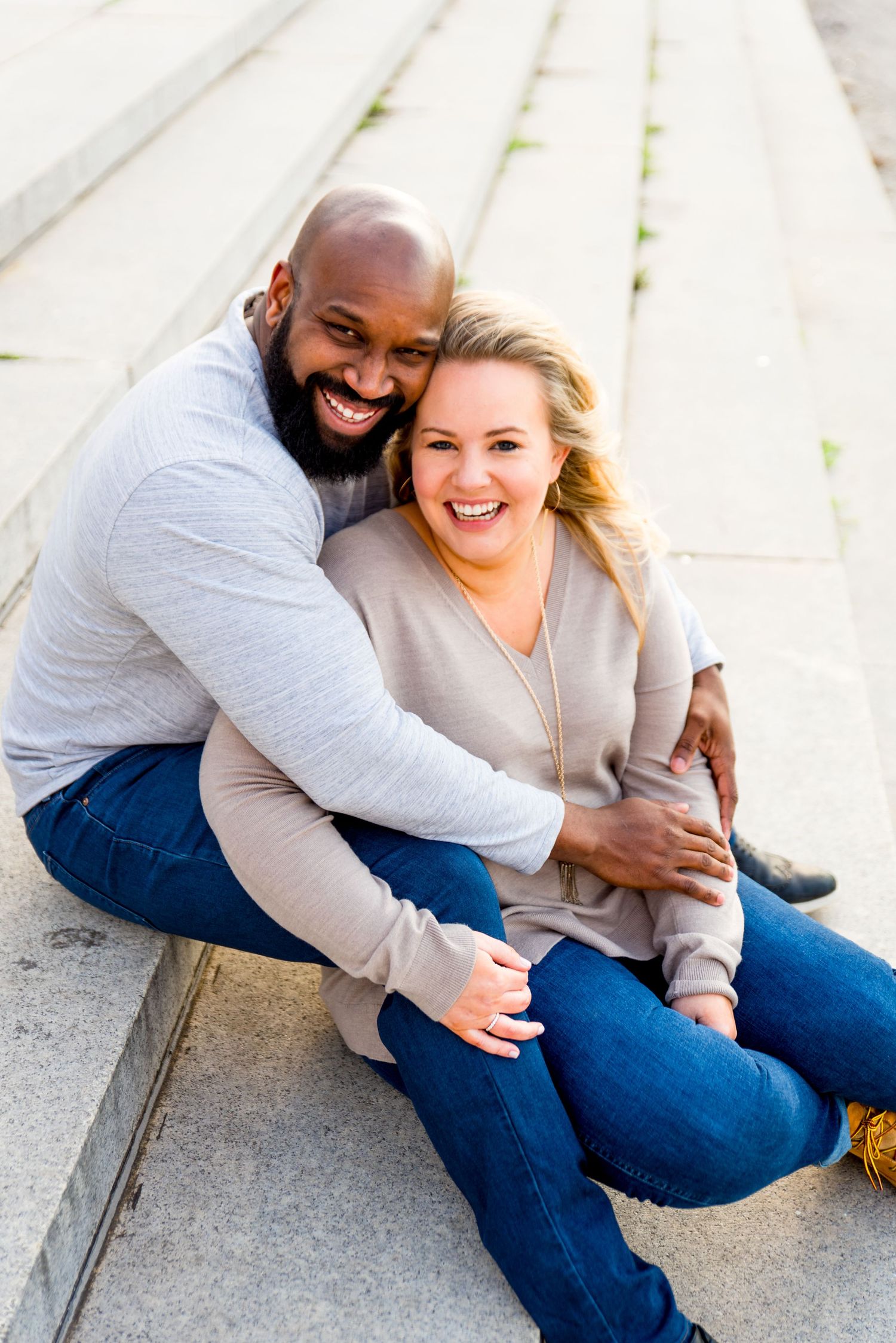 man and woman sitting on stairs in Grant Park laughing during Chicago sunrise engagement photos