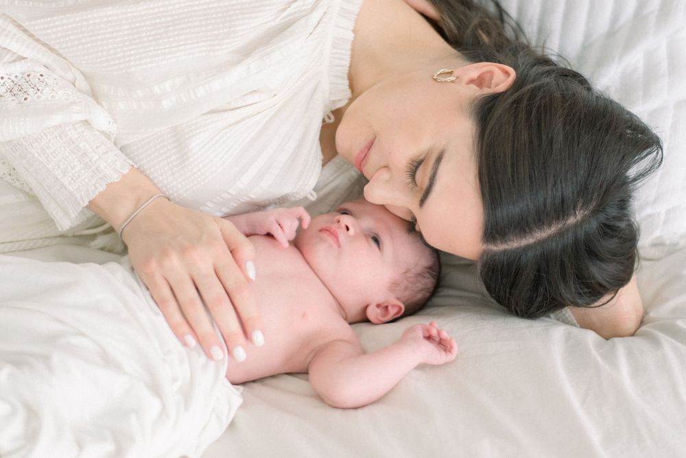mother lying with baby on bed captured by a washington dc newborn photographer