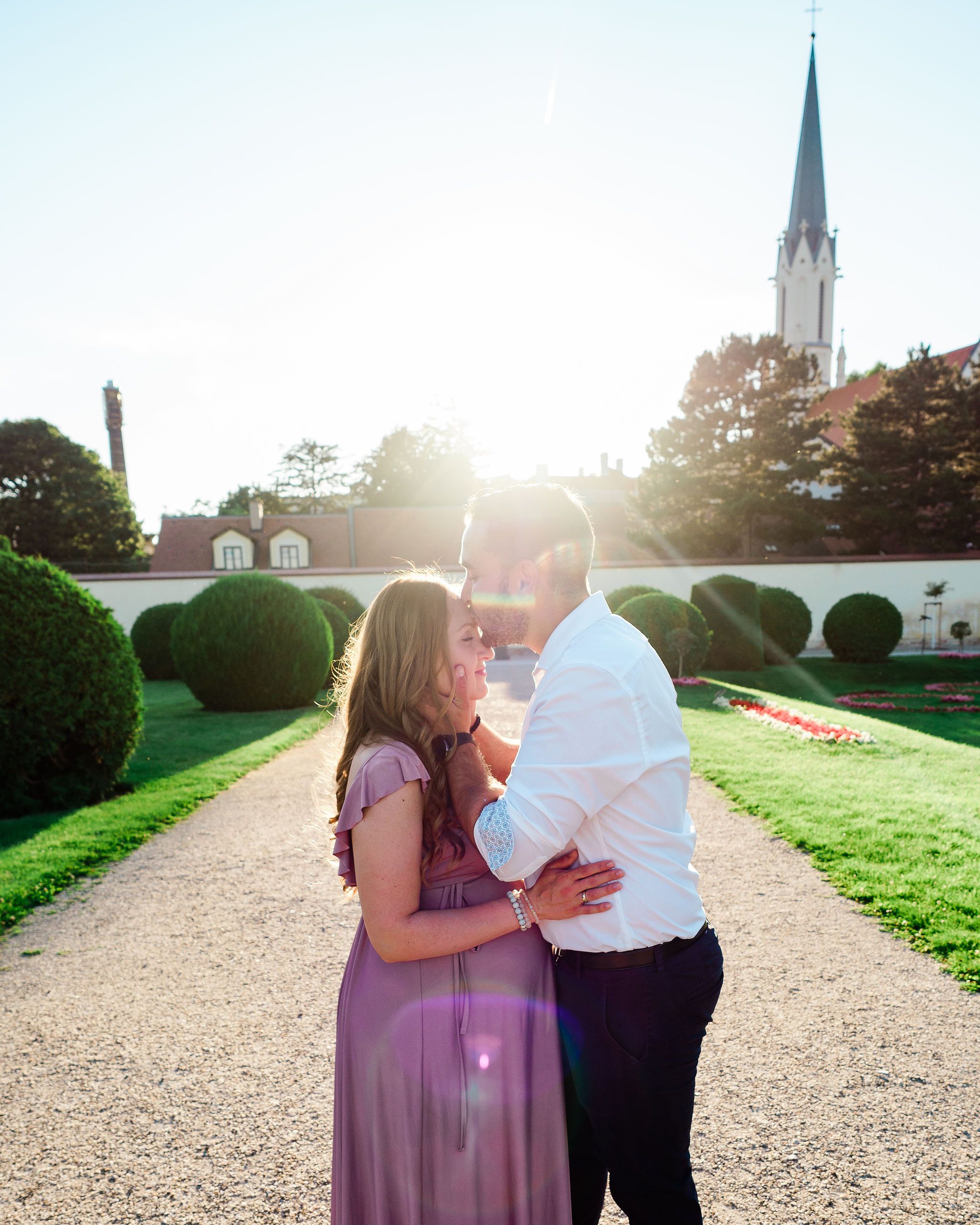 Pregnant mother and her husband hugging on a nice sunny afternoon at the Palmenhaus Garten in Vienna, Austria