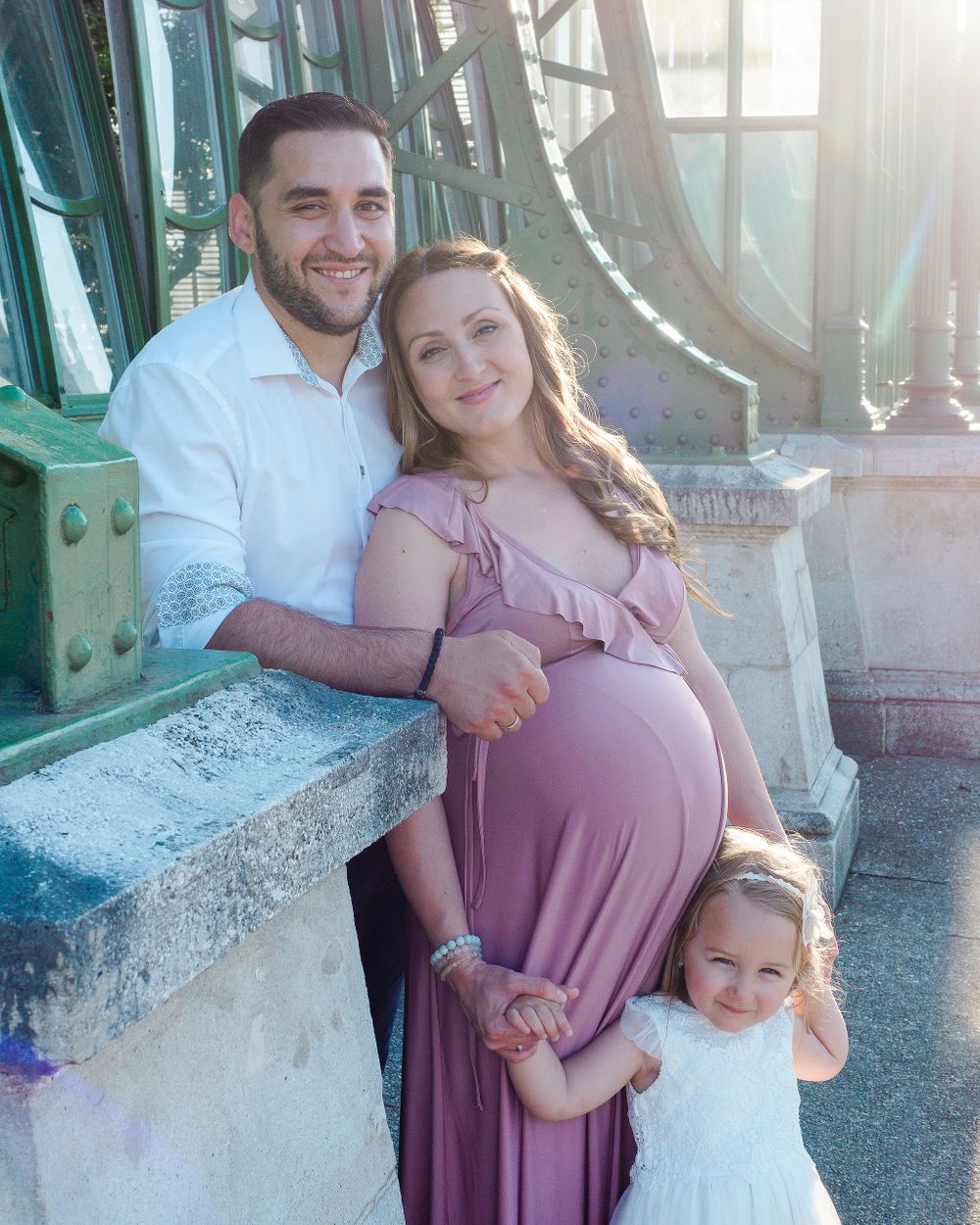 Family of three with expectant mother wearing pink posing for photograph in Vienna