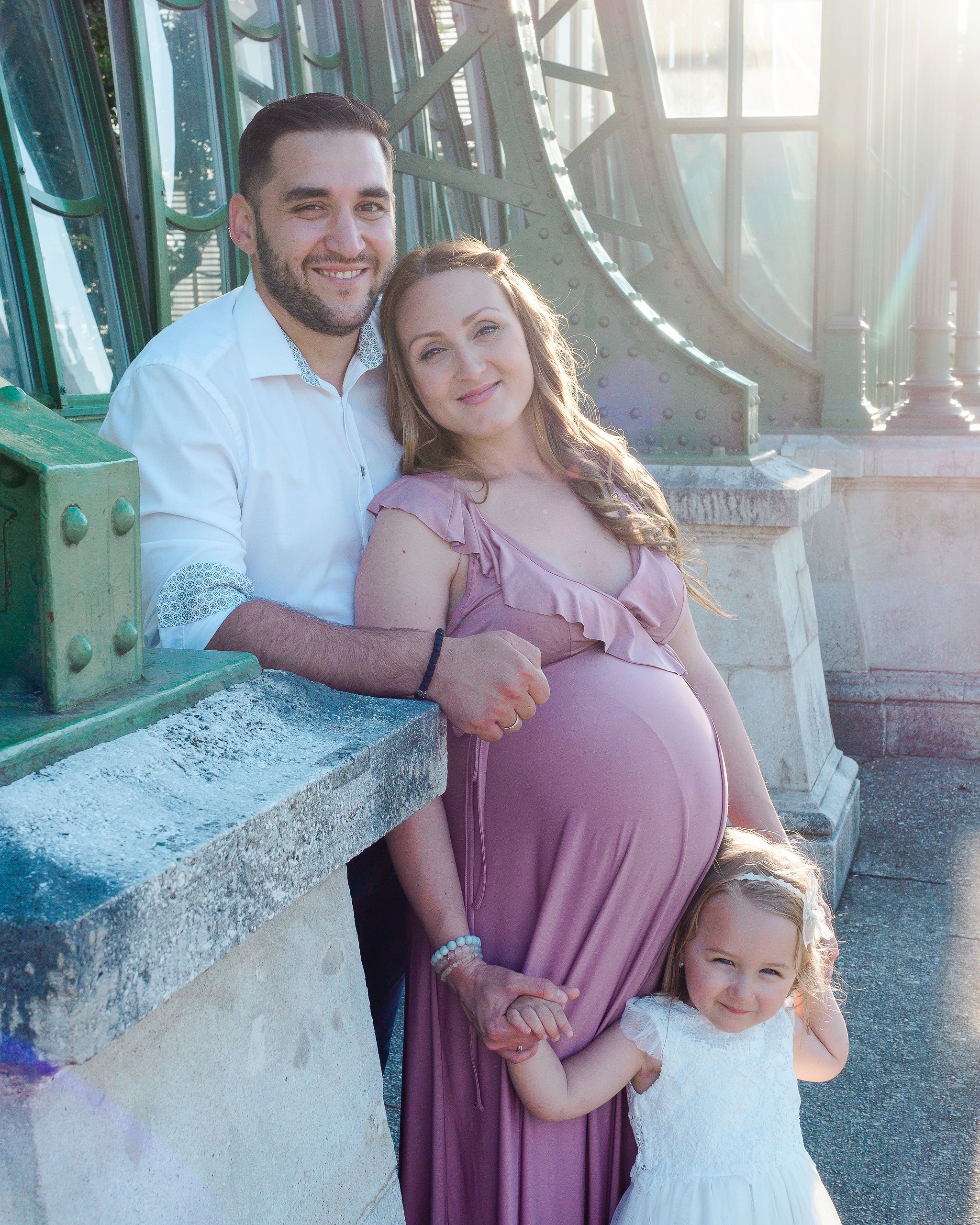 Family of three with expectant mother wearing pink posing for photograph in Vienna