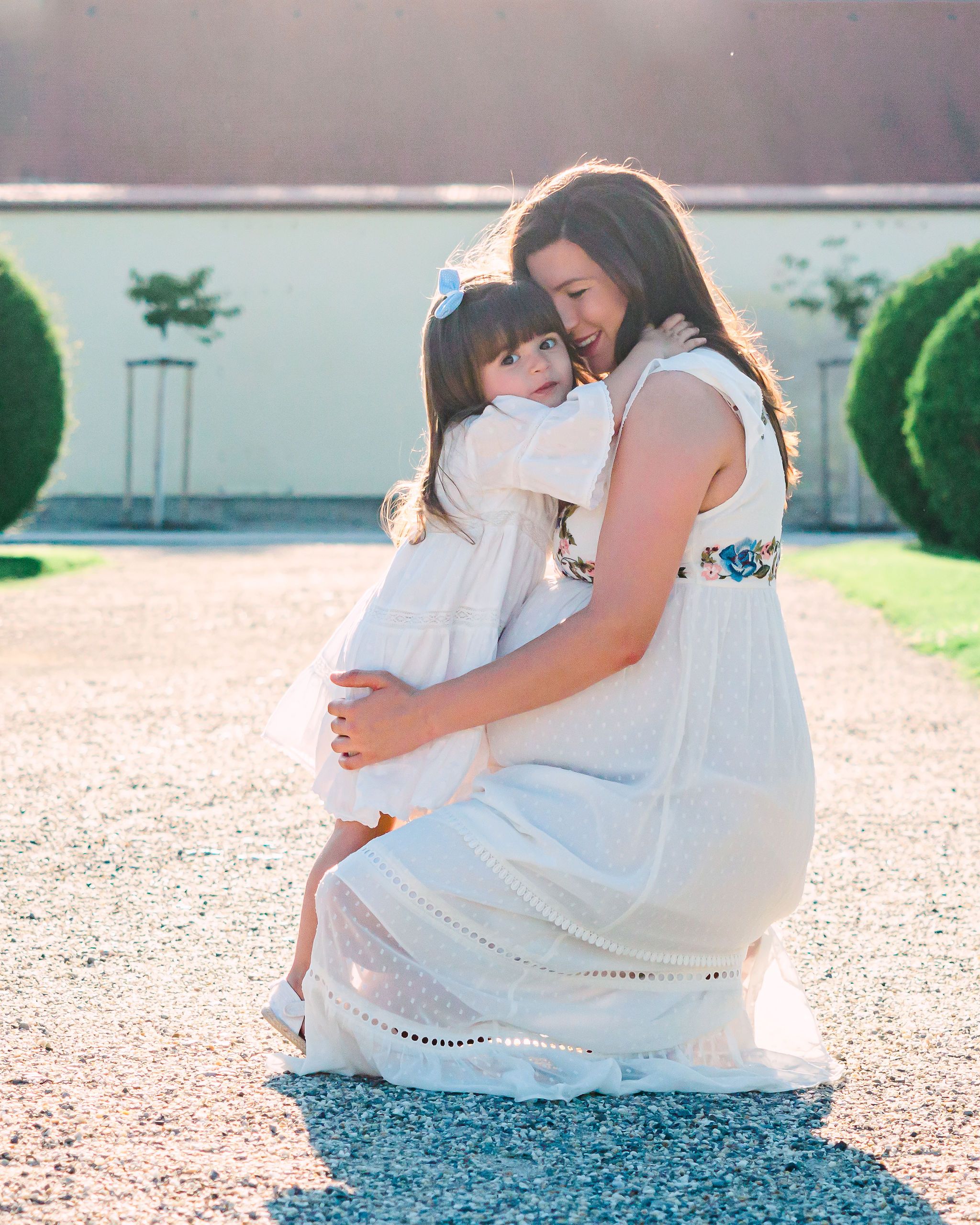 Pregnant mother lovinly hugging her daughter during sunset