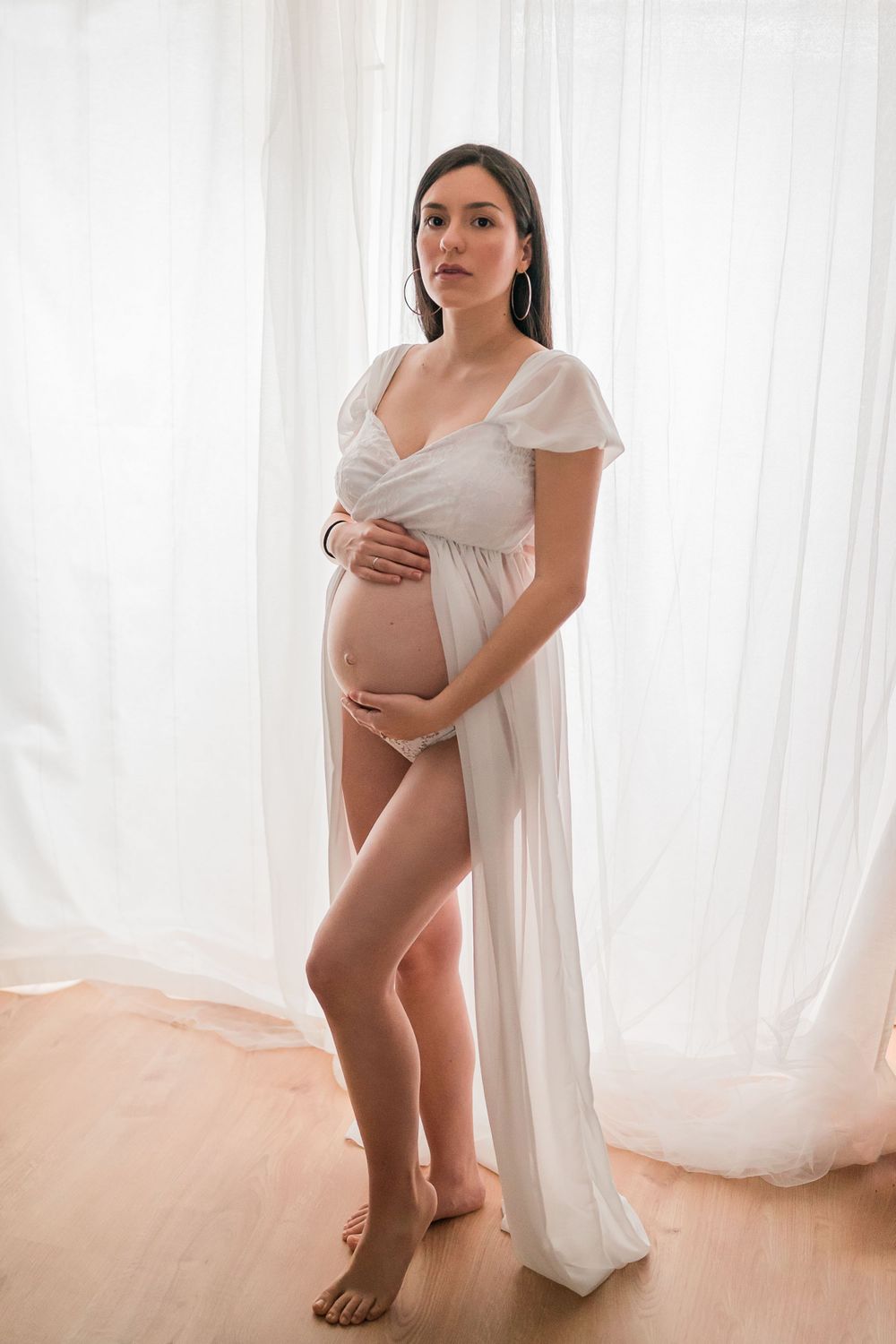 Pregnant woman wearing a white dress in studio in Mödling