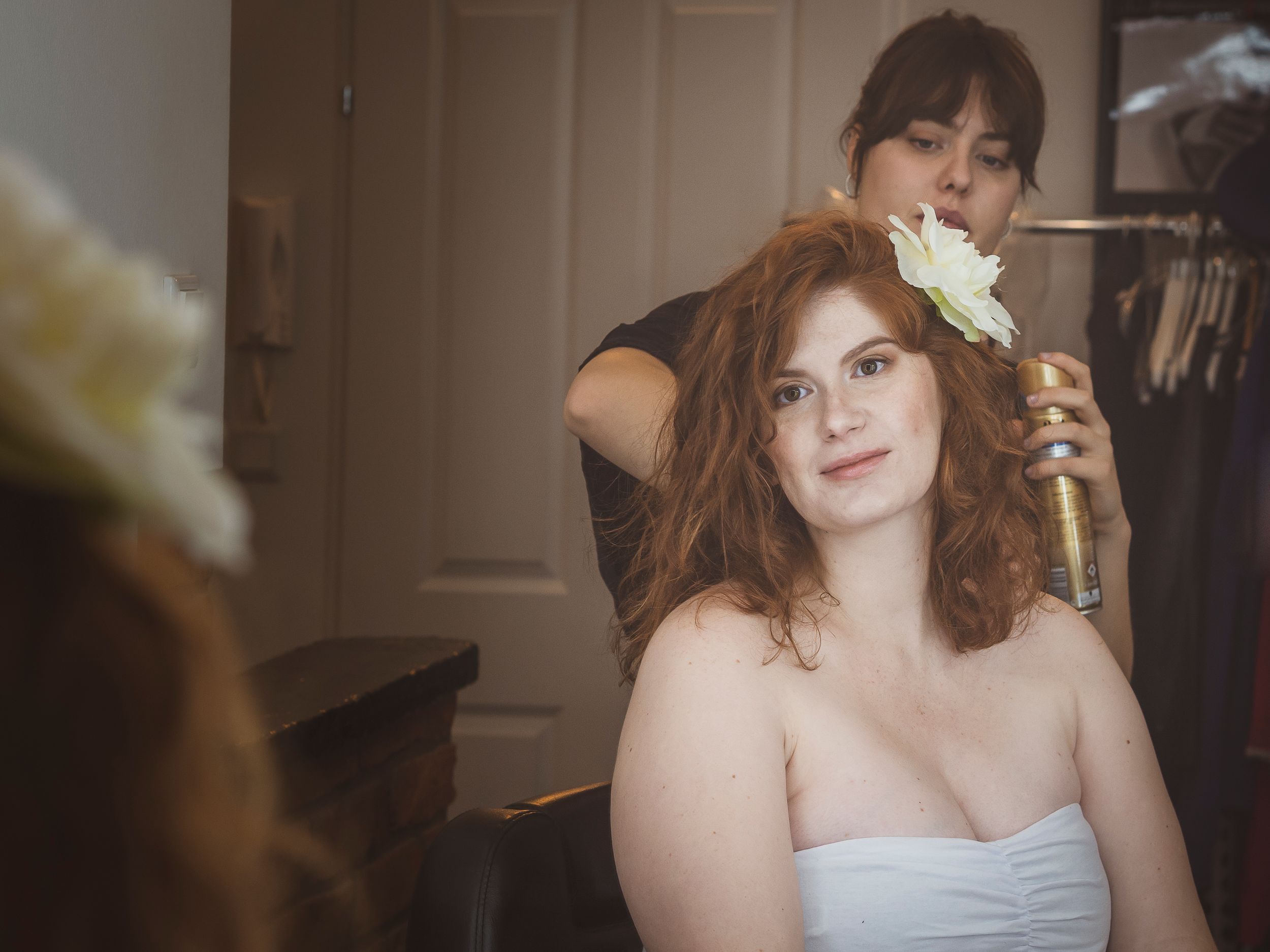 Pregnant lady looking herself in a mirror whilst a makup artists does her hair
