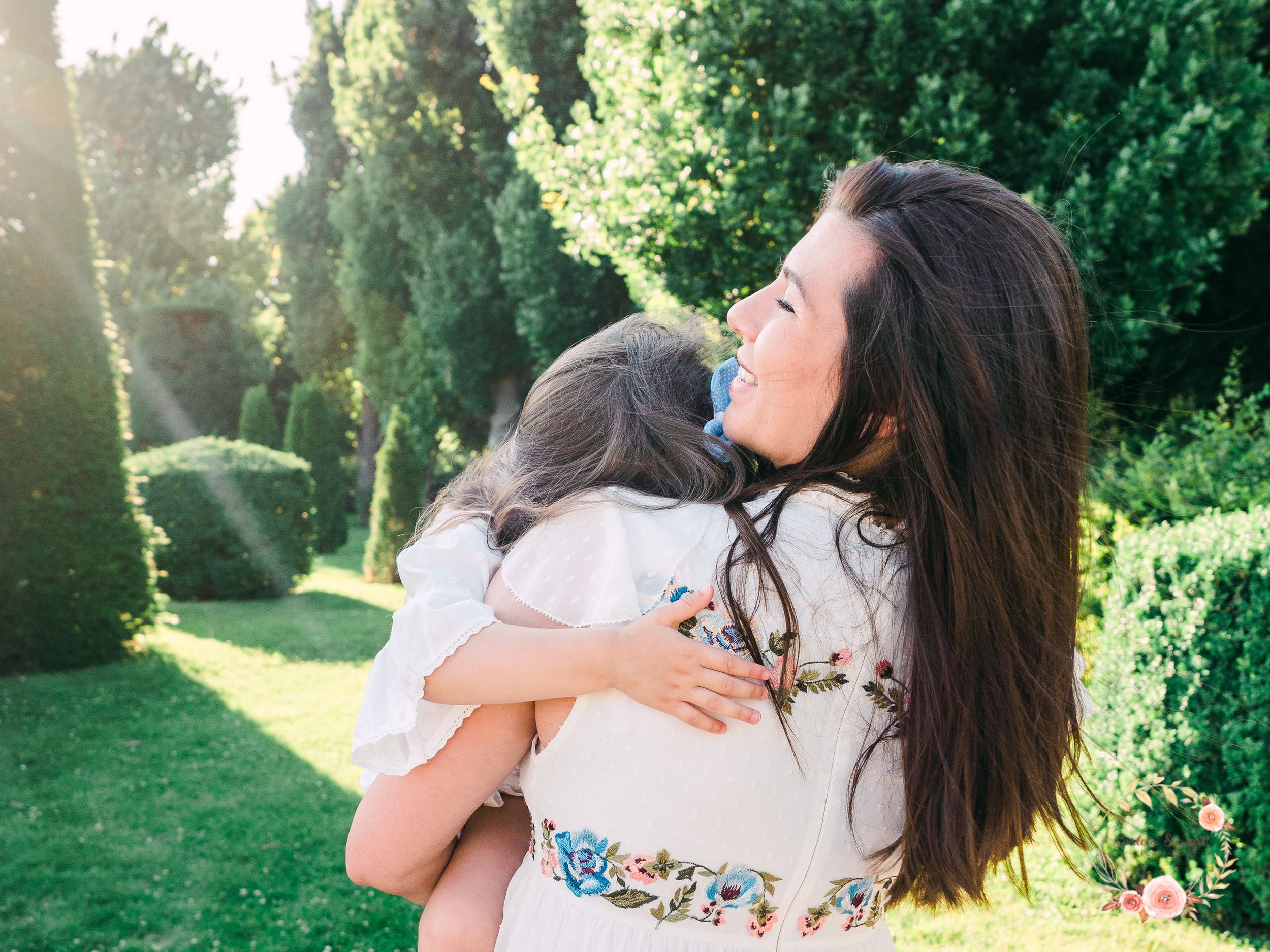 Mother holding her daughter in a sunny day at the Schönbrunn gardens in Vienna, Austria