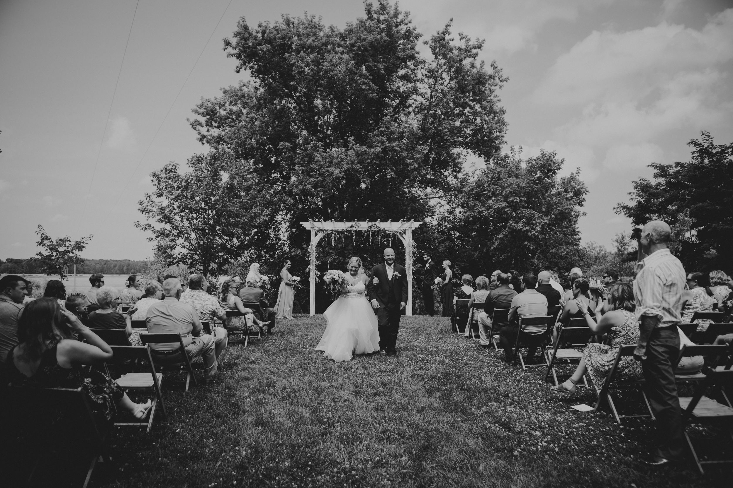 Black and white wide shot of bride and groom leaving down the aisle.