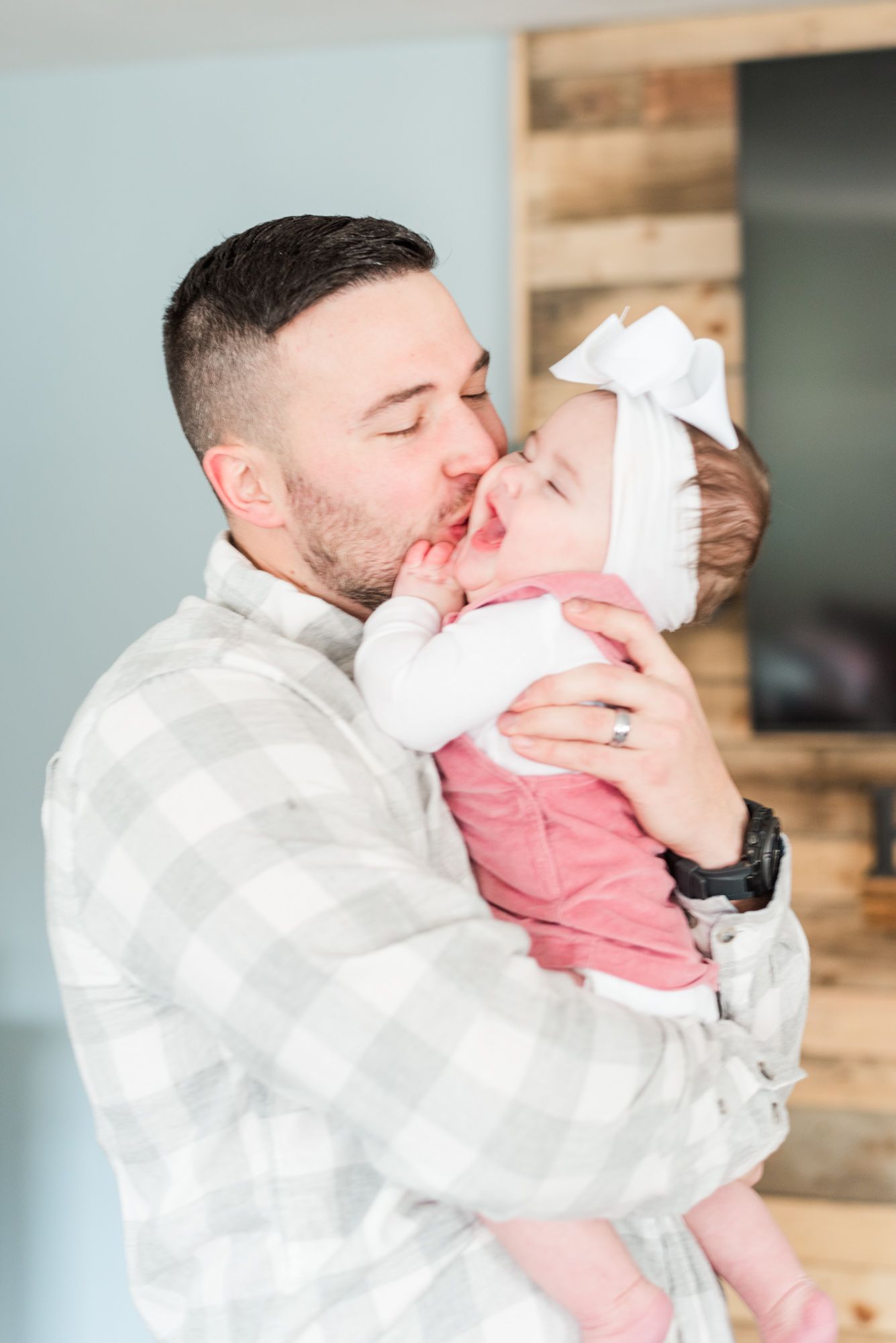 Lifestyle family photoshoot in the home with dad tickling 6 month old baby wearing bow in Gibsonia, Pennsylvania