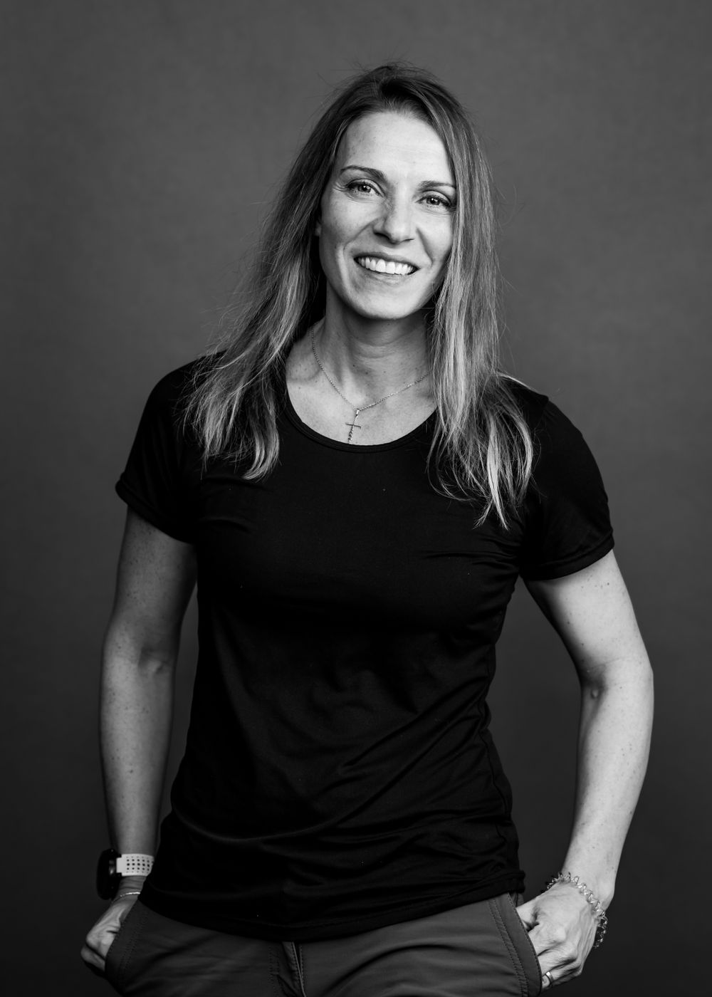 Black and white studio portrait of a person in a casual black t-shirt with long hair.